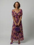 Woman wearing a purple watercolor floral mesh maxi dress with draped crossover neckline and ruched waist