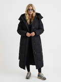 Woman wearing a long hooded quilted puffer jacket with tie belt