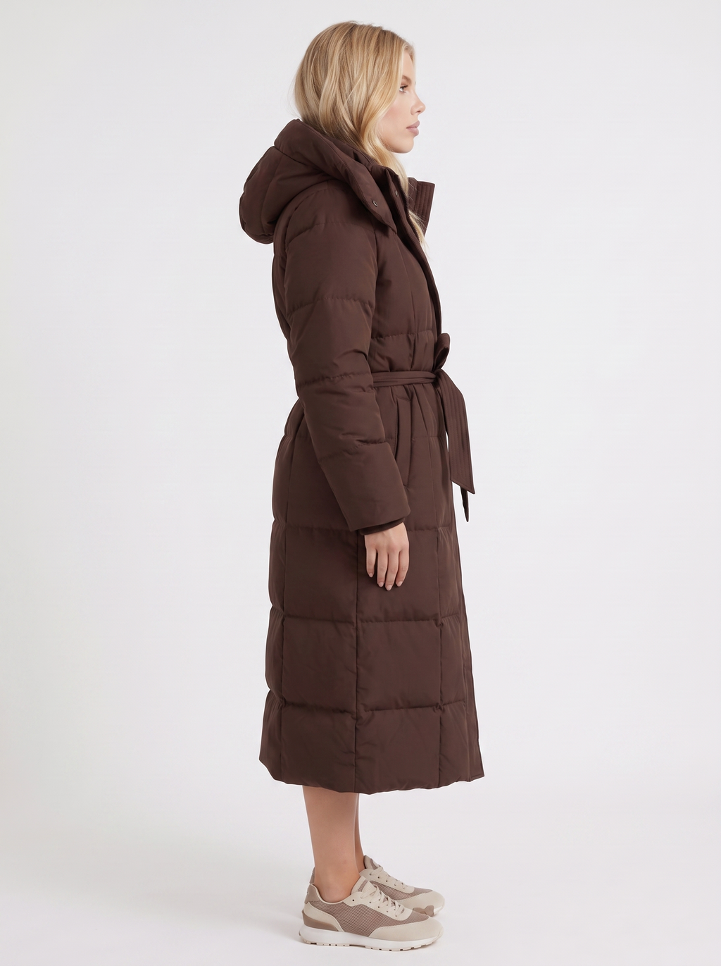 Woman wearing a long hooded quilted puffer jacket with tie belt - view 10