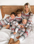 Family wearing matching Fair Isle reindeer print Christmas pajamas with white ribbed cuffs