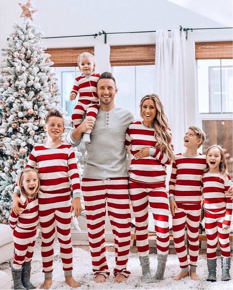 Family wearing matching red and white striped Christmas pajamas with gray cuffs