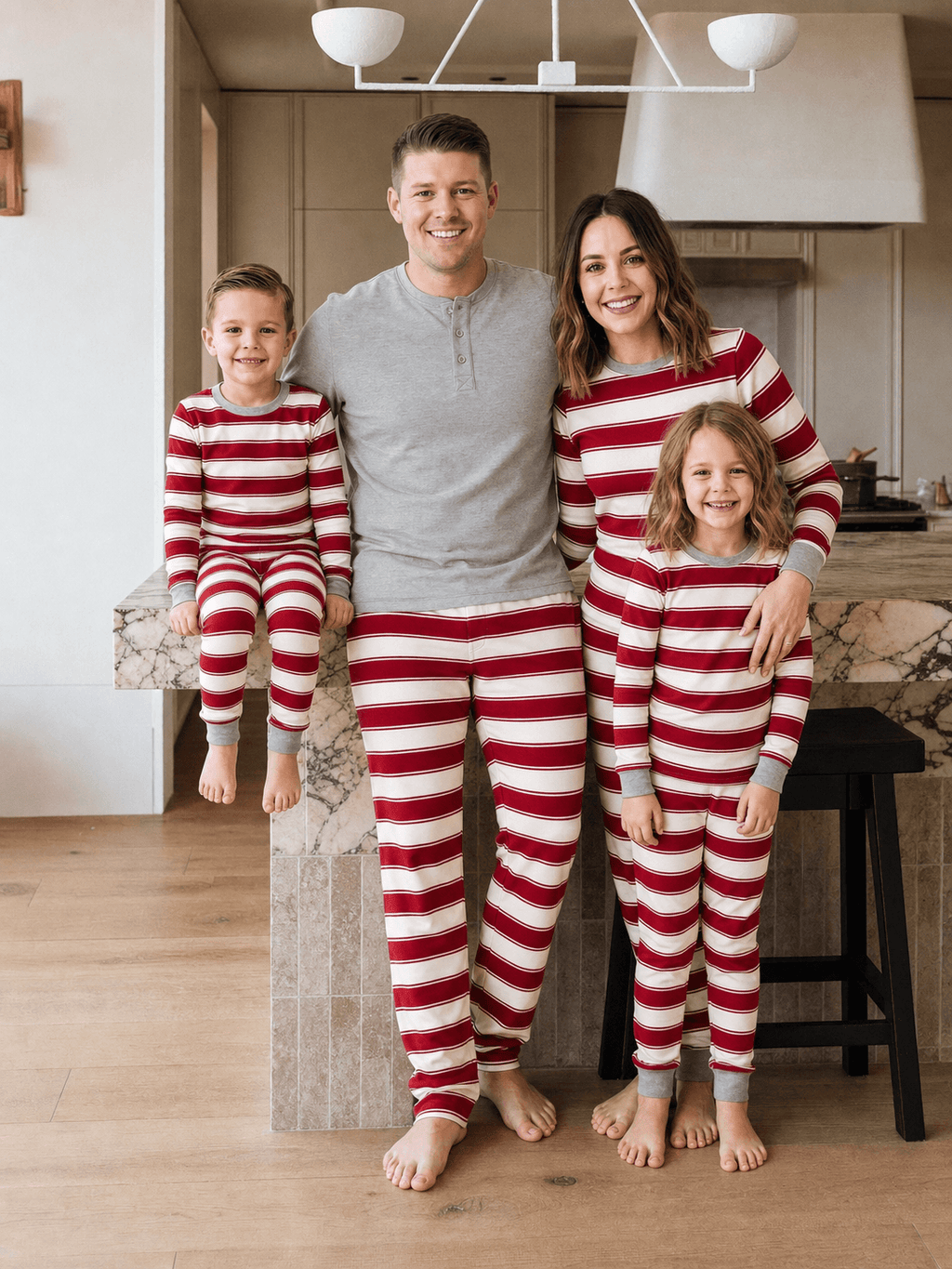 Family wearing matching red and cream striped Christmas pajamas with gray cuffs