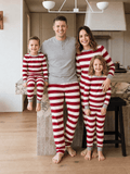 Family wearing matching red and cream striped Christmas pajamas with gray cuffs