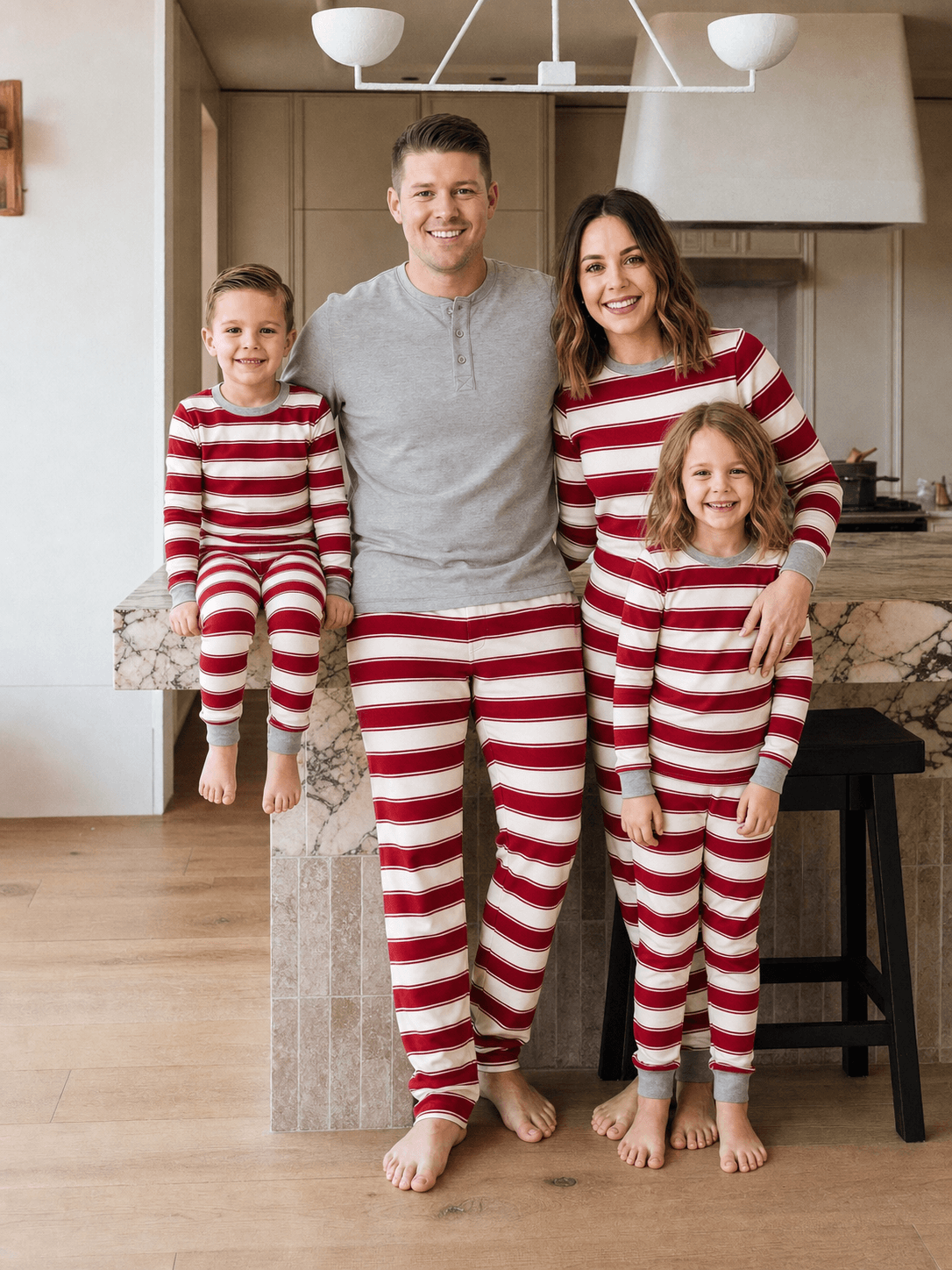 Family wearing matching red and cream striped Christmas pajamas with gray cuffs