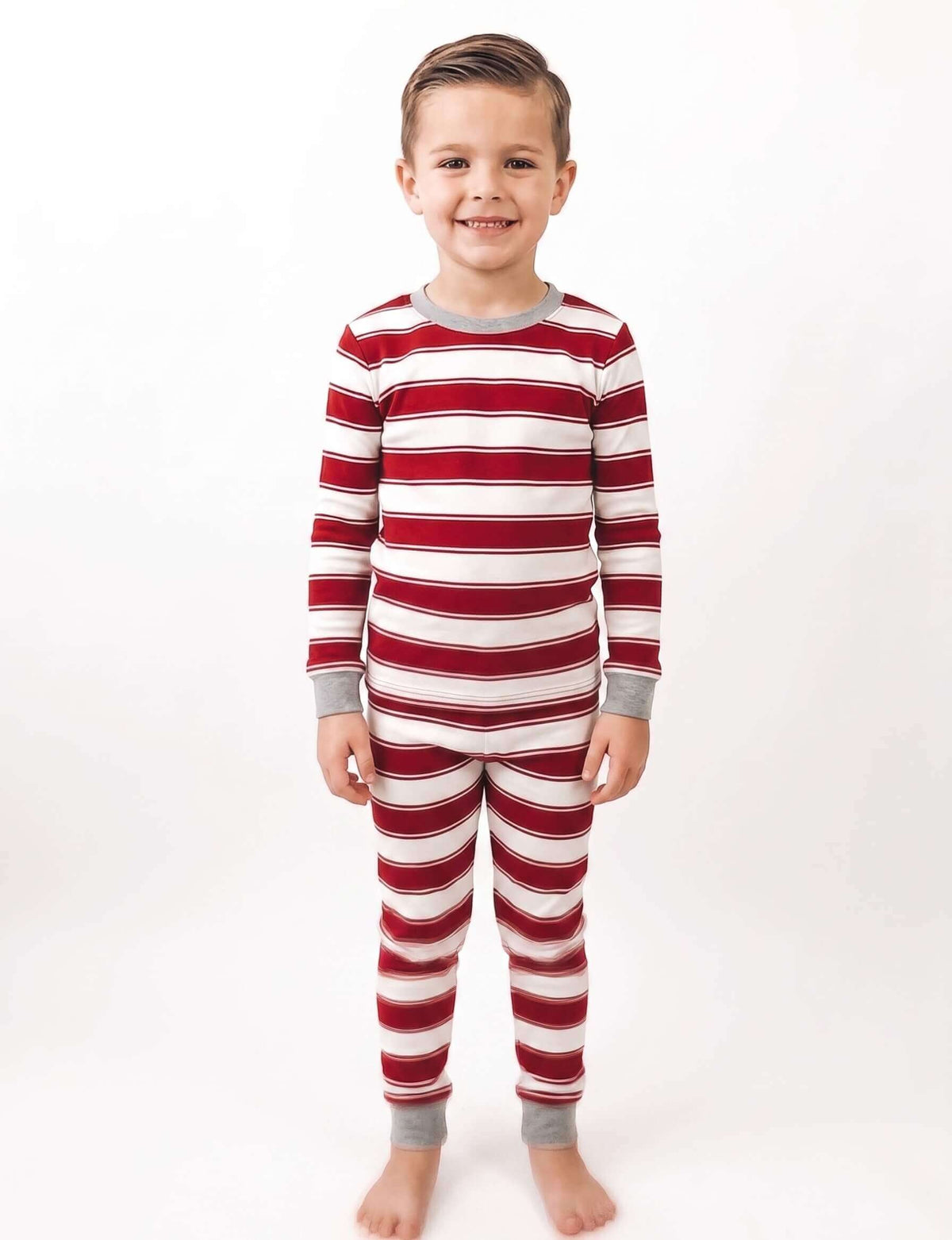 Family wearing matching red and cream striped Christmas pajamas with gray cuffs - view 10