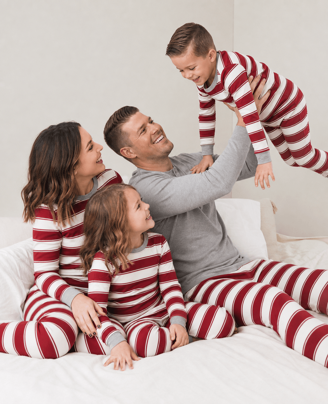 Family wearing matching red and cream striped Christmas pajamas with gray cuffs - view 3