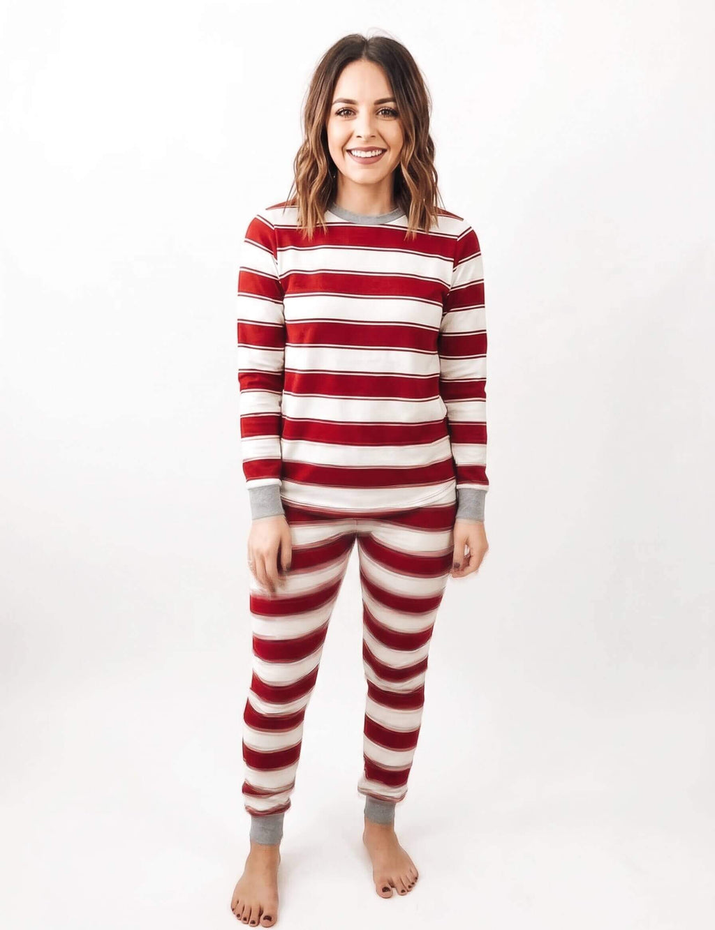 Family wearing matching red and cream striped Christmas pajamas with gray cuffs - view 9