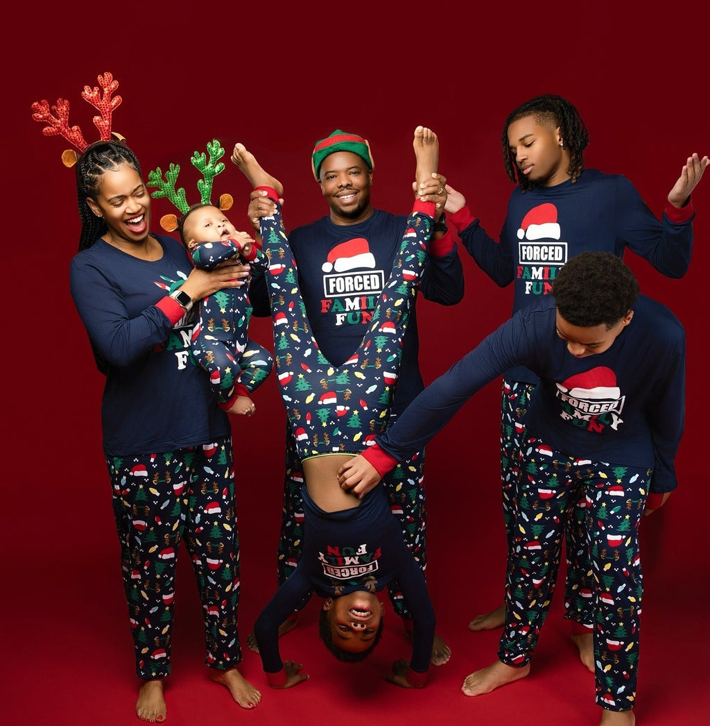 Family wearing matching navy Christmas pajamas with Santa hat graphic tops and holiday print pants