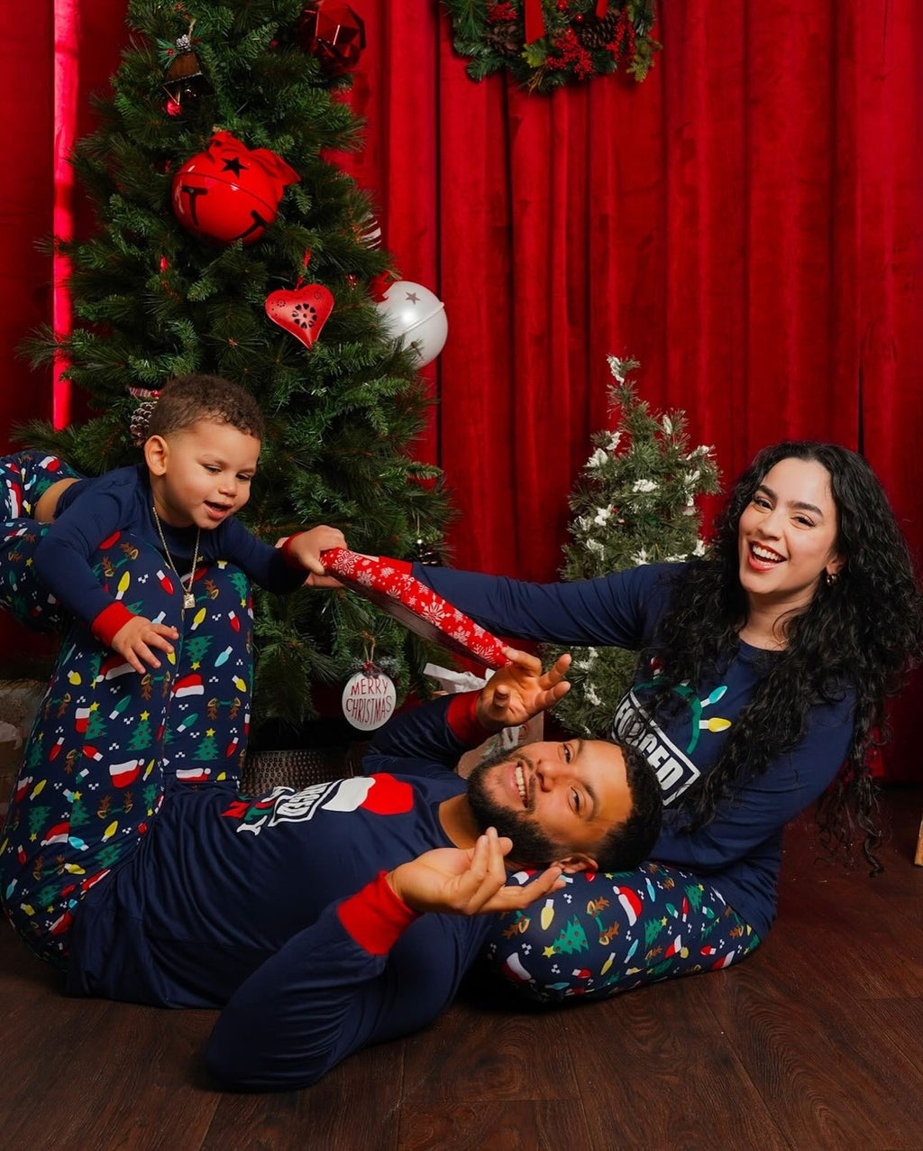 Family wearing matching navy Christmas pajamas with Santa hat graphic tops and holiday print pants - view 2