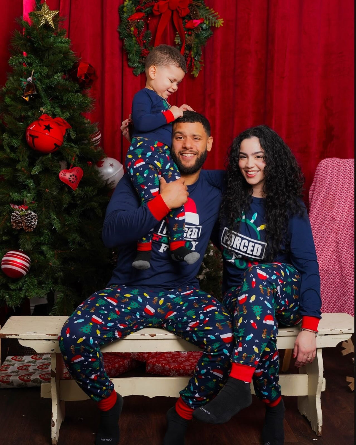 Family wearing matching navy Christmas pajamas with Santa hat graphic tops and holiday print pants - view 3