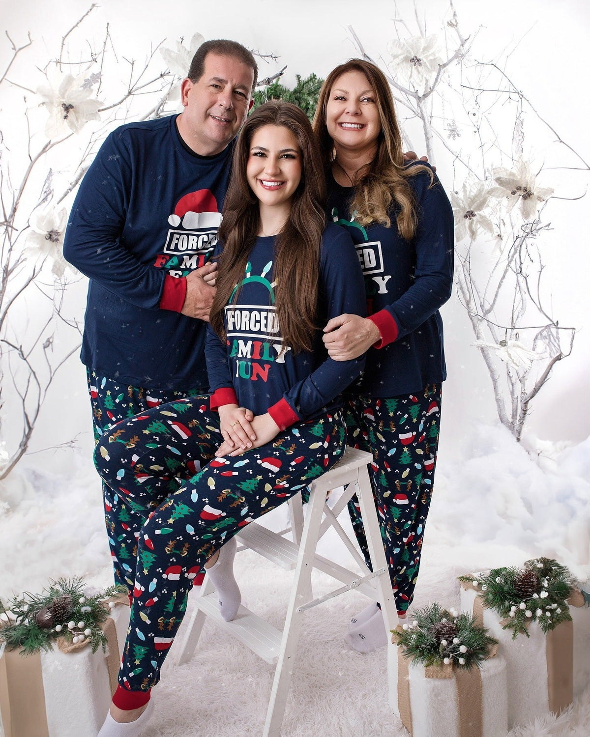 Family wearing matching navy Christmas pajamas with Santa hat graphic tops and holiday print pants - view 5