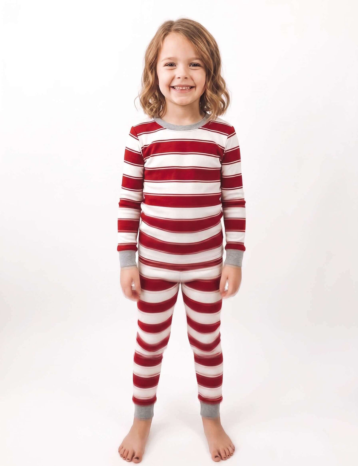 Family wearing matching red and white candy cane striped Christmas pajamas by the tree - view 11