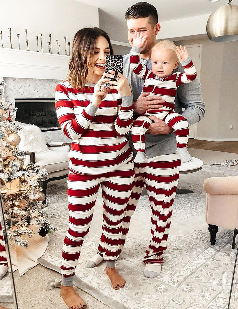 Family wearing matching red and white candy cane striped Christmas pajamas by the tree - view 13