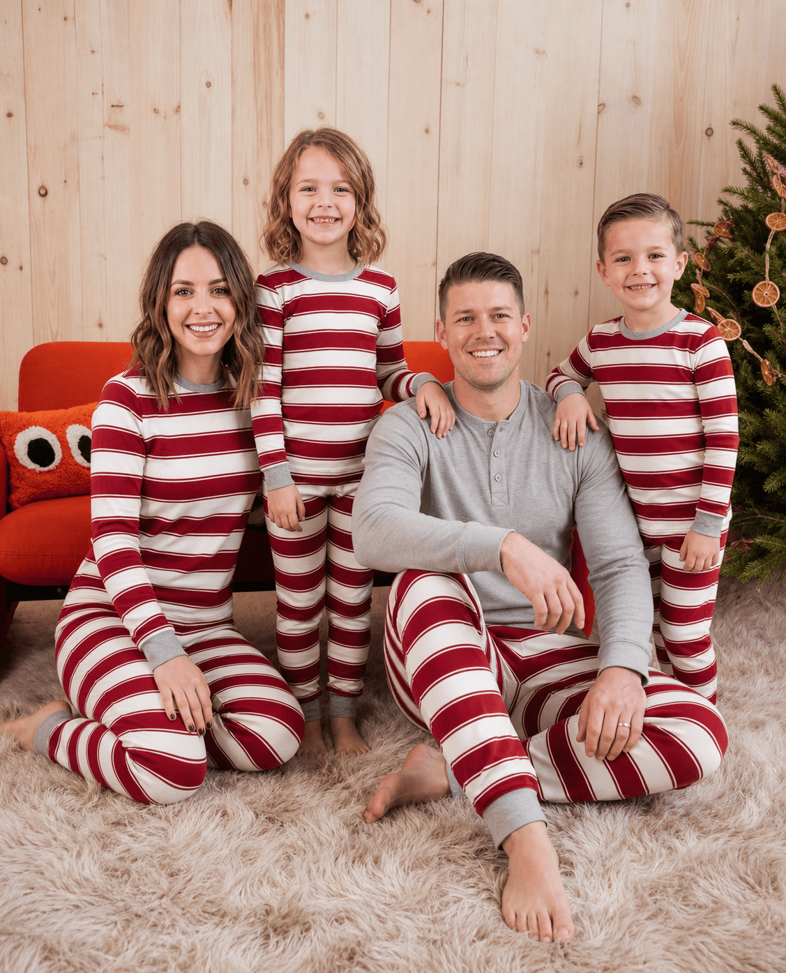 Family wearing matching red and white candy cane striped Christmas pajamas by the tree - view 5