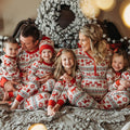 Family wearing matching red and cream reindeer print Christmas pajamas