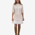 Woman wearing a cable knit sweater dress with a white pleated hem and brown knee-high boots - view 3