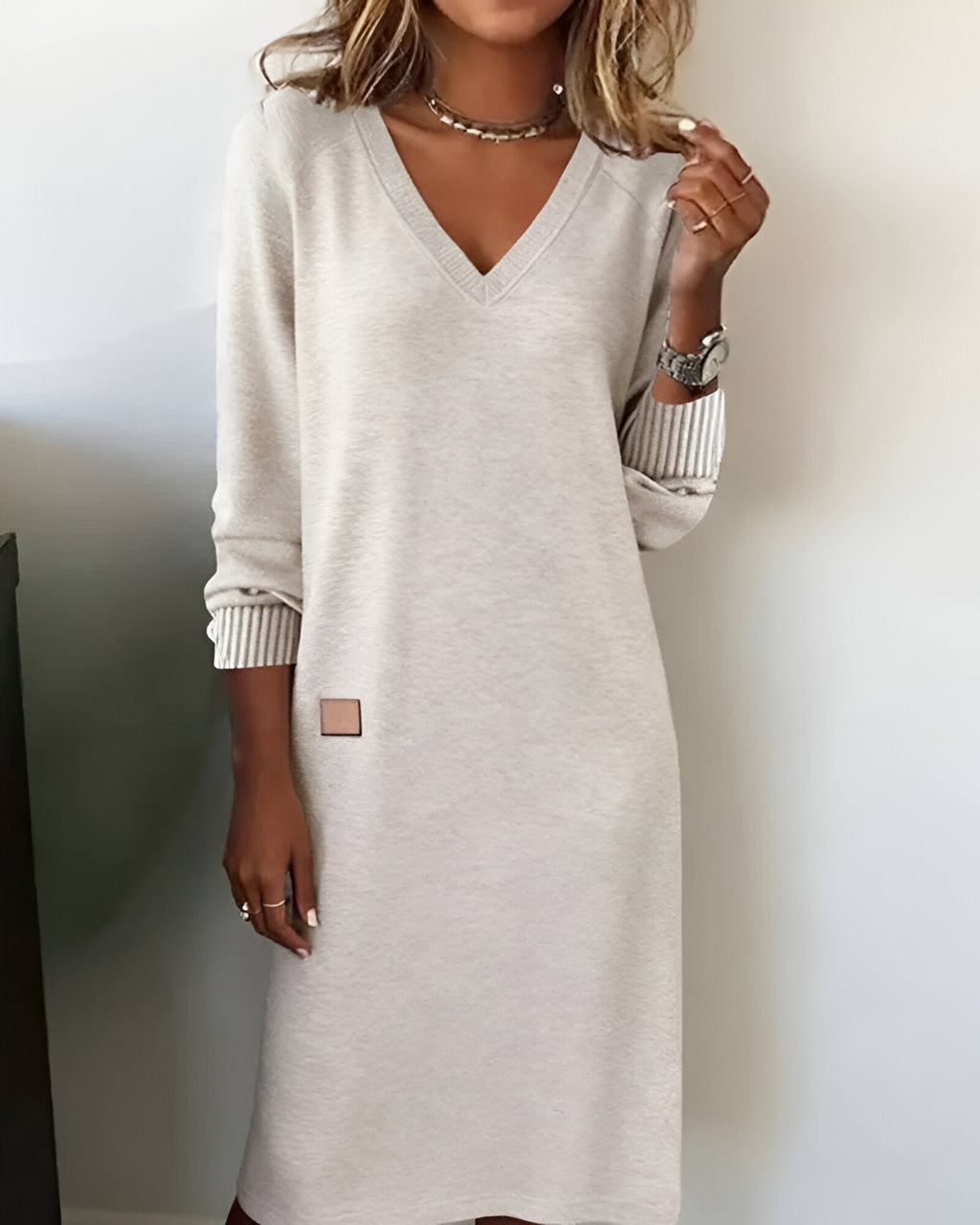 Woman wearing a V-neck long sleeve midi sweater dress with ribbed cuffs
