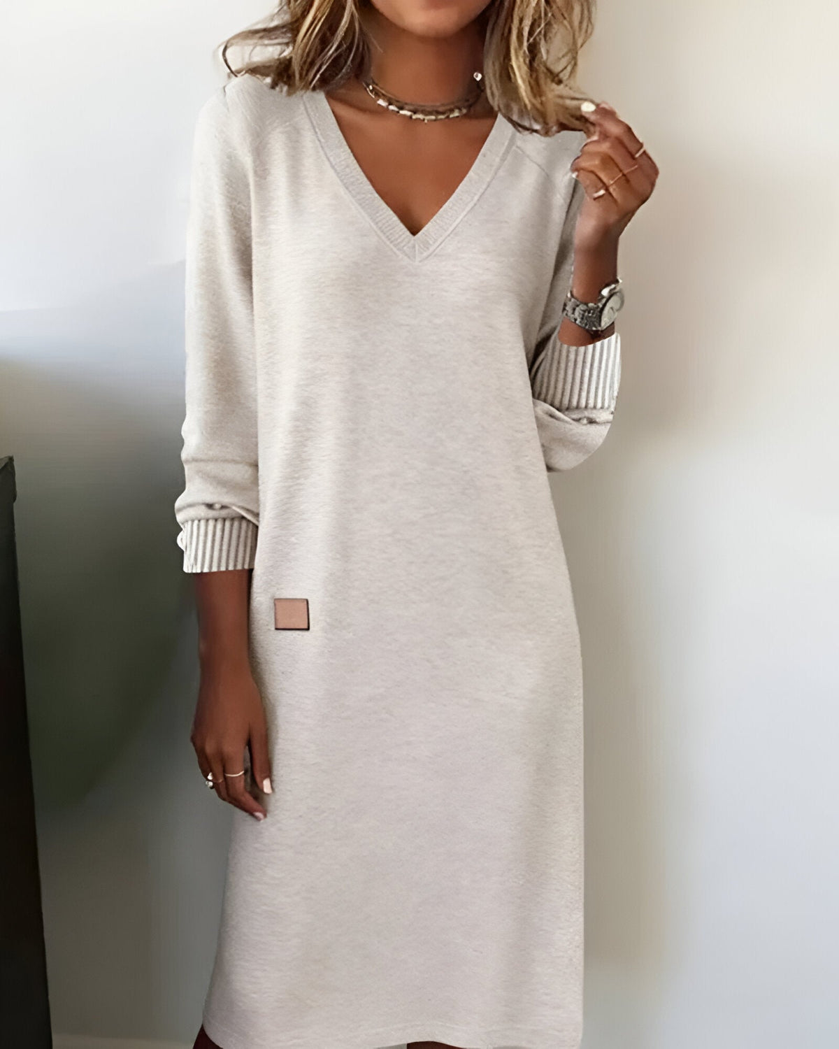 Woman wearing a V-neck long sleeve midi sweater dress with ribbed cuffs