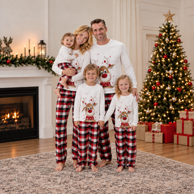 Woman in holiday pajamas with reindeer print top and red black plaid pants beside a Christmas tree
