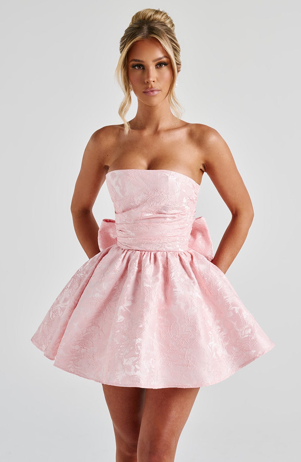 Pink jacquard homecoming mini dress with strapless bodice, corset lacing and large back bow